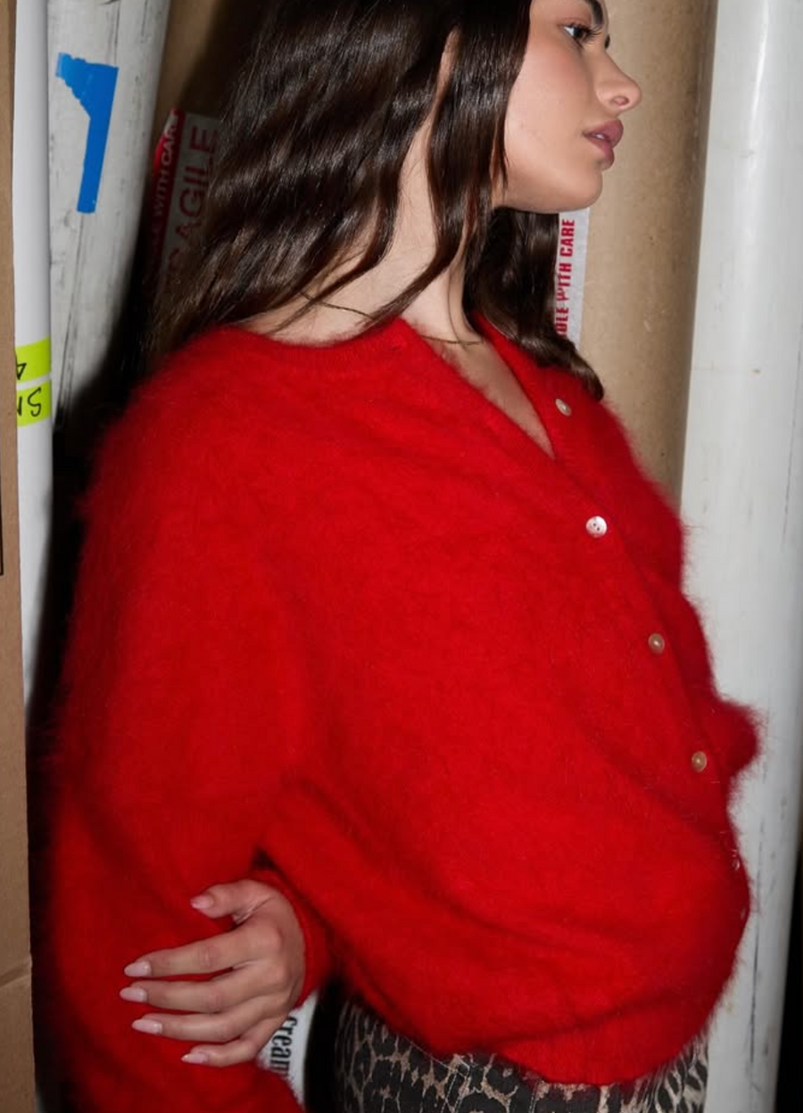 Person wearing a red cardigan with a neutral background